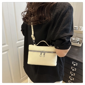 Detail of cream lychee texture crossbody bag featuring silver double zippers and handle