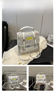 Detailed view of mini white polka dot backpack with yellow cartoon patch and top handle