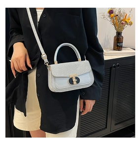 Detail of silver sequin handbag with metal lock shown in a minimalist setting
