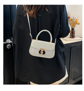 Detailed view of silver sequin square bag with golden T-shaped metal clasp and strap