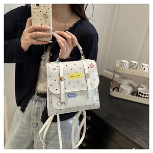 Detail of white polka dot bag with cat patch and lace trim shown held in hand