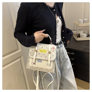 Detailed view of a white polka dot handbag with yellow tags and blue bubble pattern logo