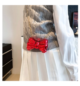 Glossy red metallic bow mini bag with gold chain strap shown on a model's shoulder
