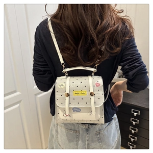 Detail of a mini grey polka dot backpack featuring decorative patches and magnetic buckles