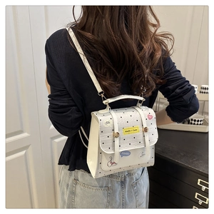 Detailed view of white polka dot backpack with cartoon patches on a model back