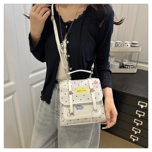 Polka dot crossbody bag with yellow patch shown on model in a cozy indoor setting