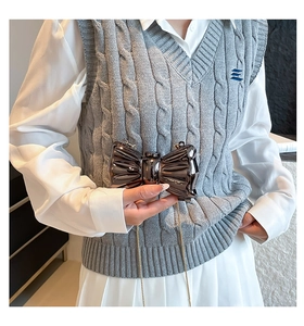 Detail of metallic butterfly clutch bag with chain strap shown on a model