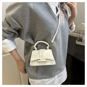 Detail view of white pebbled leather mini hourglass crossbody bag worn by a model