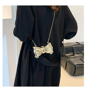 Golden bow-shaped hard shell clutch bag with metallic mirror finish and thin chain strap