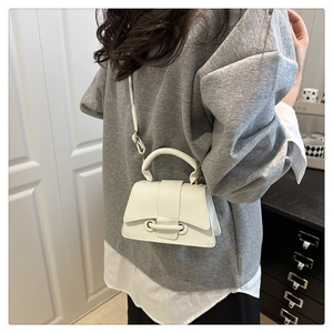 Detail of cream white pebbled leather mini handbag with top handle and crossbody strap