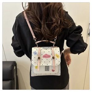 Detail of white polka dot backpack with pink handles and cloud patch on the flap