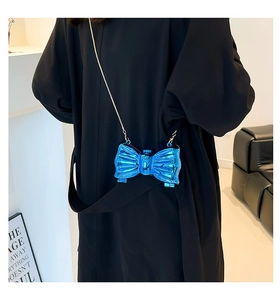 Detail of the butterfly bow metallic blue shoulder bag with a gold chain strap