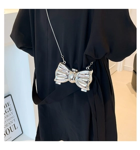 Detail of silver metallic bow-shaped mini bag with glossy mirror finish and chain strap