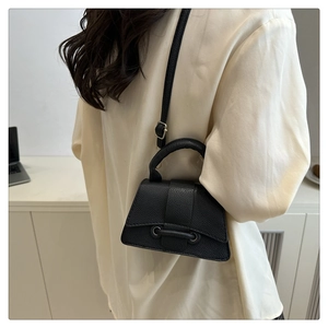 Detail view of black lychee texture mini bag with hourglass base and crossbody strap