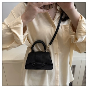 Mirror selfie showing a small black lychee leather handbag with a crossbody strap