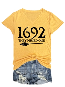 Detail of yellow V-neck tee with witch broom print paired with distressed denim shorts