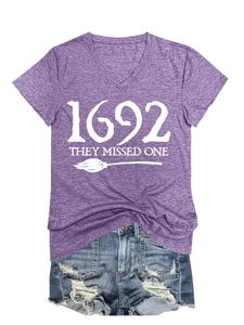 Detail of purple V-neck T-shirt with 1692 They Missed One witch slogan and broom print