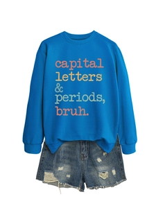 Flat lay of royal blue sweatshirt with artistic typography and distressed denim shorts