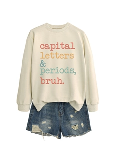 Flat lay of cream crewneck sweatshirt with slogan and distressed denim shorts set