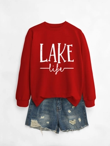 Flat lay of red LAKE life sweatshirt paired with distressed blue denim shorts