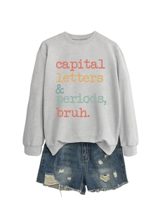 Close-up of light grey sweatshirt with colorful text and distressed denim shorts