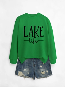 Flat lay of green round neck LAKE life sweatshirt paired with distressed blue denim shorts