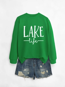 Detail of bright green LAKE life crewneck sweatshirt paired with distressed denim shorts
