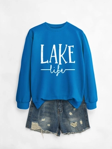 Flat lay of blue long sleeve LAKE life sweatshirt with distressed denim shorts