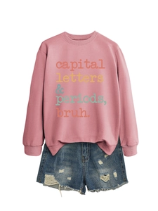 Pink crewneck sweatshirt with 'capital letters' text and distressed denim shorts