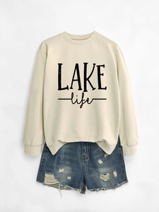 Flat lay of a beige LAKE life sweatshirt paired with distressed blue denim shorts