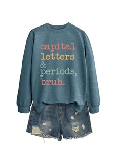 Detailed flat lay of blue crewneck sweatshirt with graphic text and ripped denim shorts