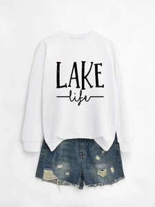 Flat lay of white crewneck sweatshirt with LAKE life text and distressed denim shorts