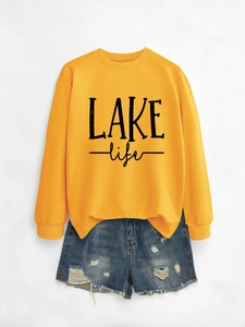 Close-up of ginger yellow LAKE life crewneck sweatshirt with distressed denim shorts