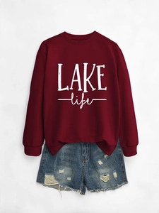 Detail view of burgundy LAKE life sweatshirt paired with distressed denim shorts on a plain background