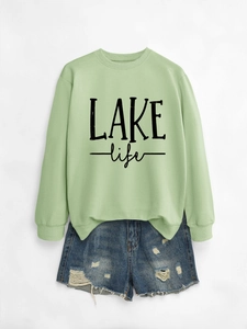Detail of light green sweatshirt with LAKE life print and distressed denim shorts