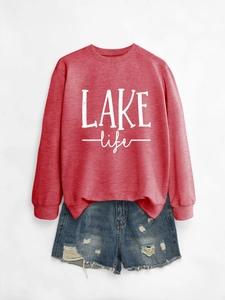 Close-up of brick red long sleeve sweatshirt with white LAKE life lettering and denim shorts