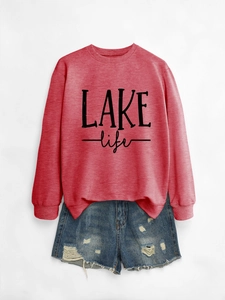 Flat lay of red LAKE life sweatshirt with ribbed cuffs and blue distressed denim shorts
