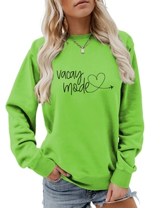Close-up of bright green sweatshirt featuring black vacay mode lettering and heart airplane path