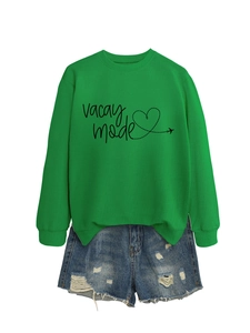 Flat lay of a bright green sweatshirt with vacay mode text and distressed denim shorts