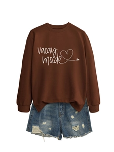 Detail of Vacay Mode print on brown sweatshirt paired with distressed blue denim shorts