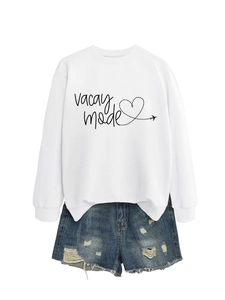 Flat lay of white vacay mode sweatshirt with heart graphic and distressed denim shorts
