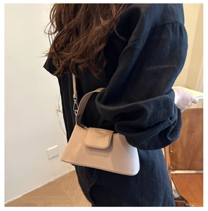 Detail of beige faux leather handbag featuring silver hardware and debossed brand logo