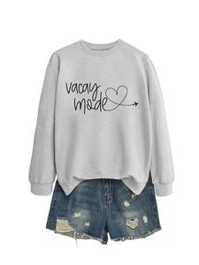 Detail of the Vacay Mode heart print on a grey long sleeve sweatshirt and denim shorts