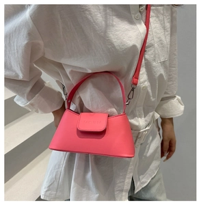 Détail d'un mini sac carré rose vif avec logo embossé et crochet en métal argenté