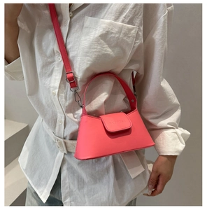 Detail of pink mini handbag showing the textured leather flap and metallic logo engraving