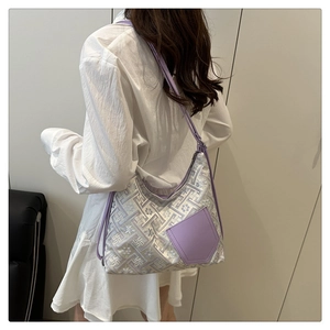 Detail of silver woven shoulder bag with floral texture and purple strap on model