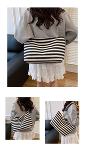 Detail of striped canvas tote bag with elegant gold chain and black leather shoulder strap