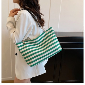 Detail of green and white striped tote bag with black leather and gold chain straps
