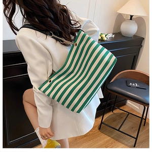 Close-up of green and white striped tote bag with leather and gold chain strap details