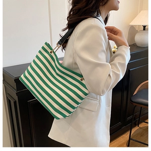 Detail of green and white striped canvas tote bag with gold rings and leather strap